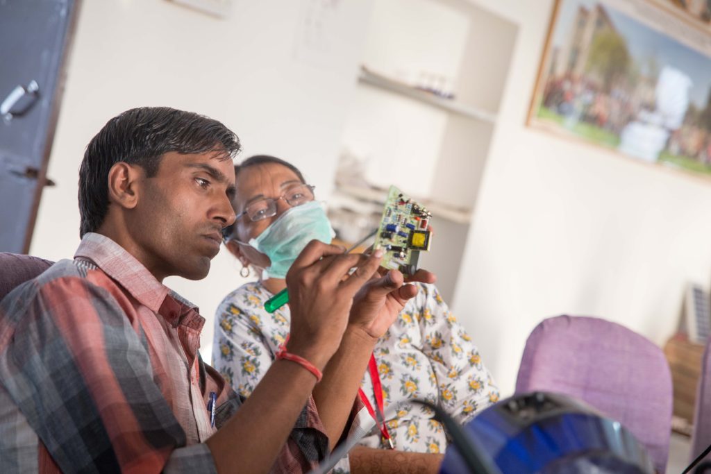 Solar Trainer, Gordhan evaluates the soldered circuit board put together by Solar Mama Zenaida from the Philippines.