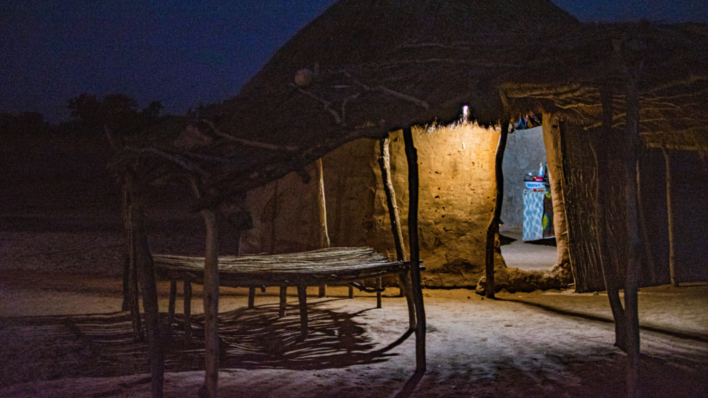 A rural home in Senegal at night with a solar light shining. This home has been electrified by a rural woman solar engineer, trained by Barefoot College International